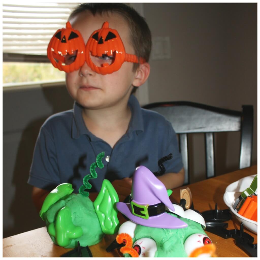 monster making play dough wearing pumpkin glasses