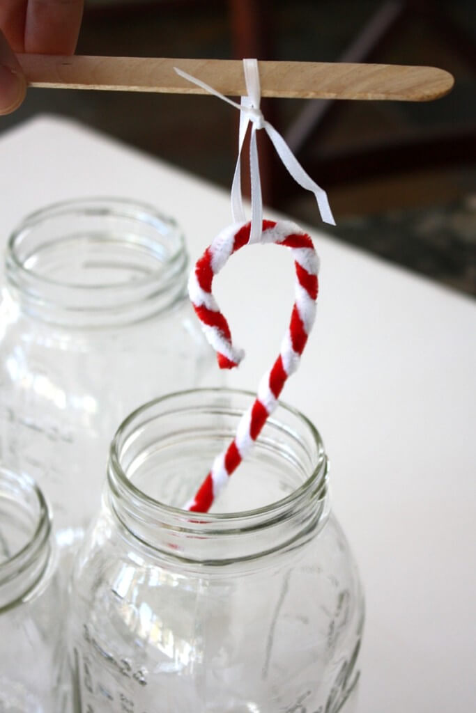 Setting up sticks for making Christmas crystal candy canes with kids - Check out this great science experiment for kids! They can learn how to grow crystal candy canes with a Christmas chemistry science activity! Fun experiment for kids! #STEM #science #candycane
