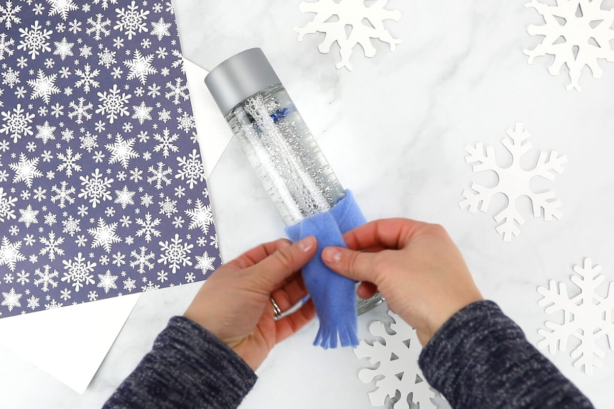 tying blue fleece scarf on snowman sensory bottle