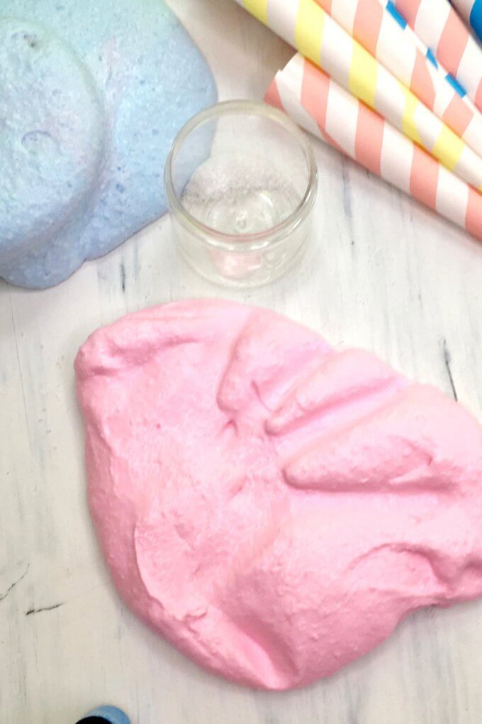 Pink fluffy cotton candy slime on table with hand print in it