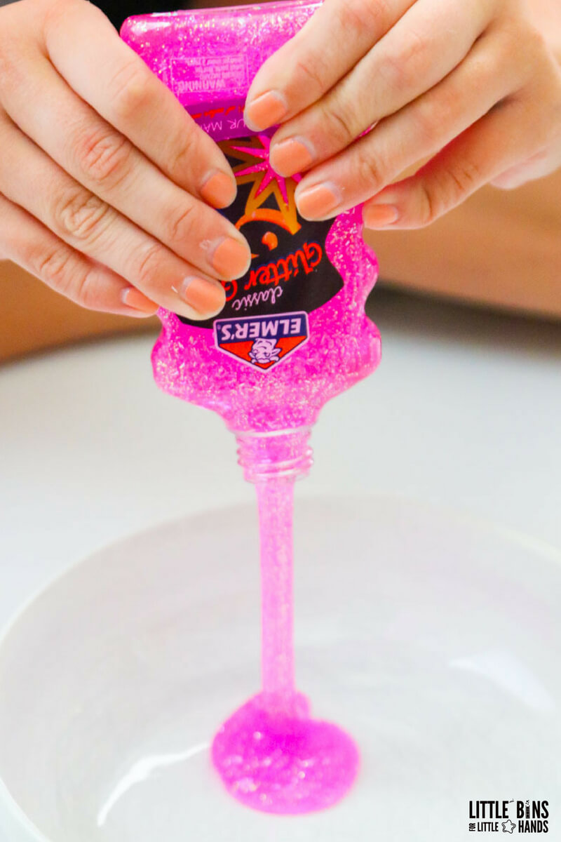 squeezing Elmers glitter glue into bowl for pink slime