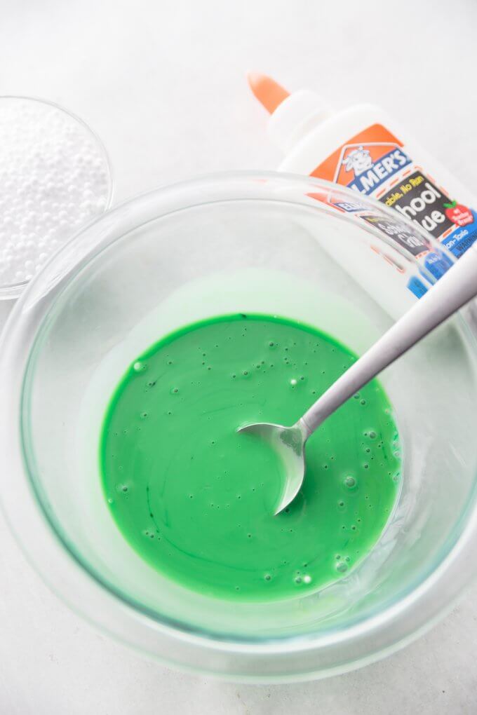 glue, water, and green food coloring in bowl for Halloween floam