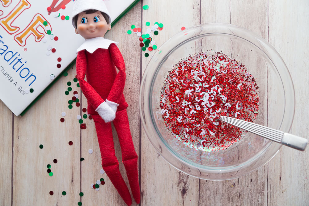 Elf on the shelf with christmas confetti and slime ingredients in bowl