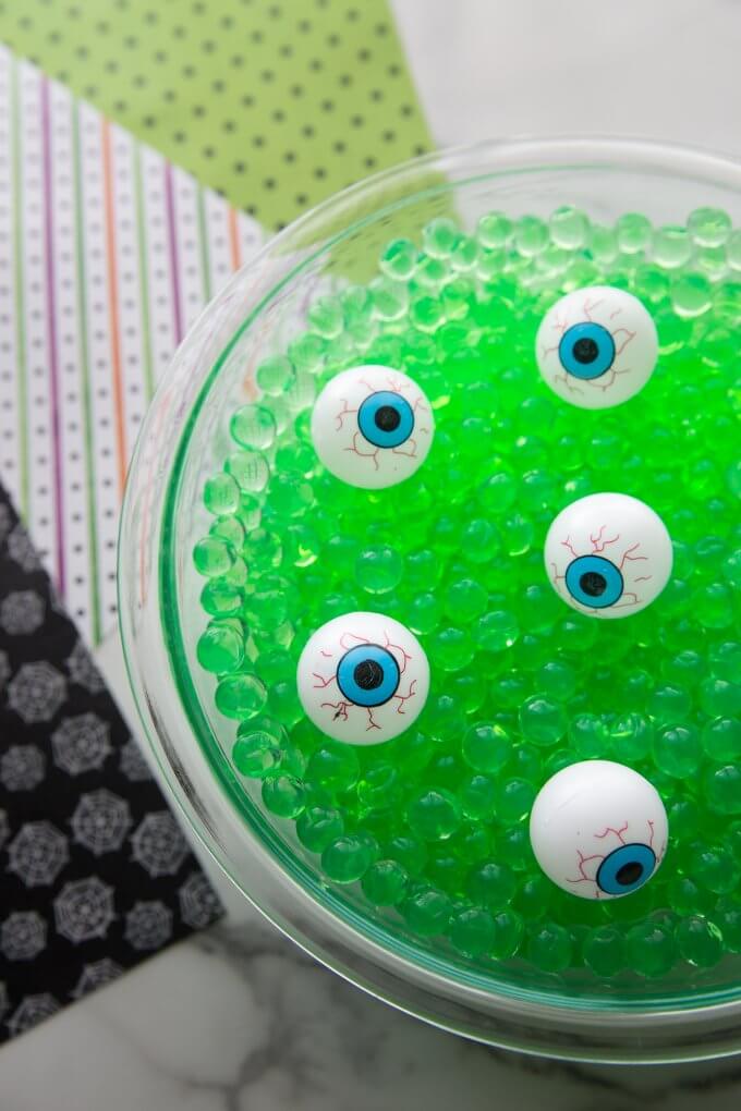 plastic eyeballs in green water beads bowl sensory bin